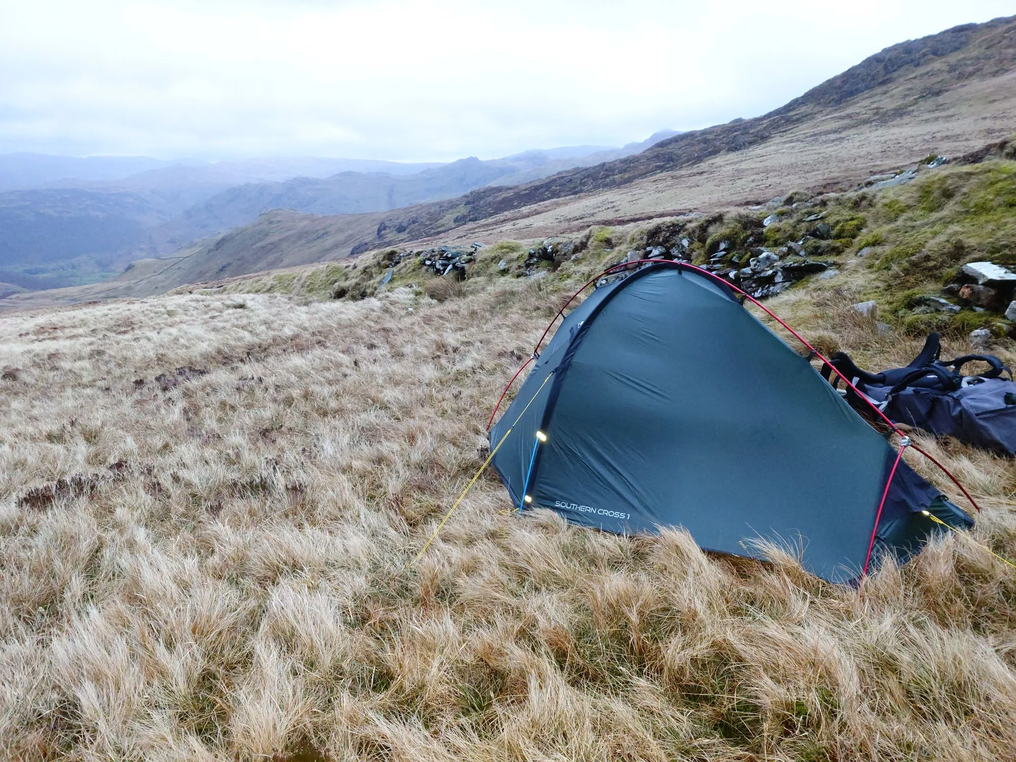 A tent pitched on open fellside, hills beyond
